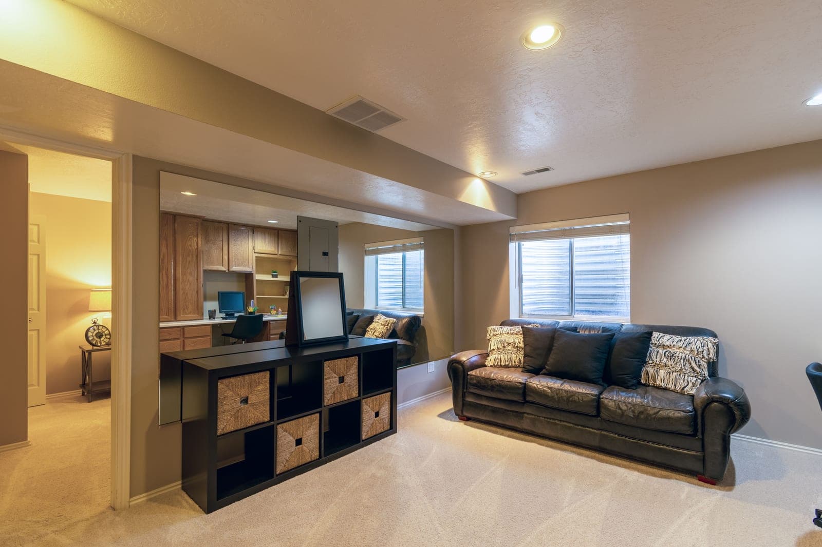 A finished basement living space with a sofa, carpet and high windows