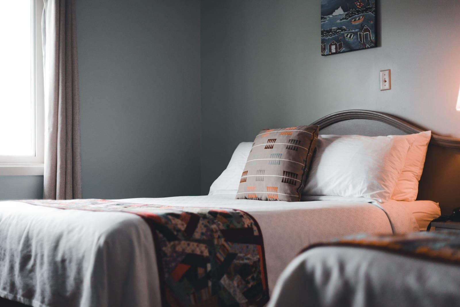 A made bed with pillows, sheets and a quilt in a bedroom