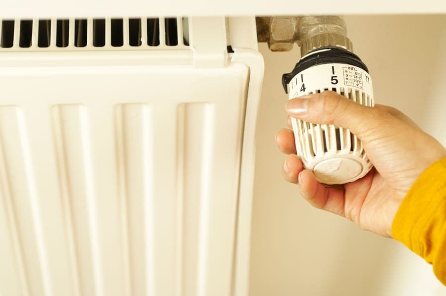 A hand adjusting a wall-mounted control