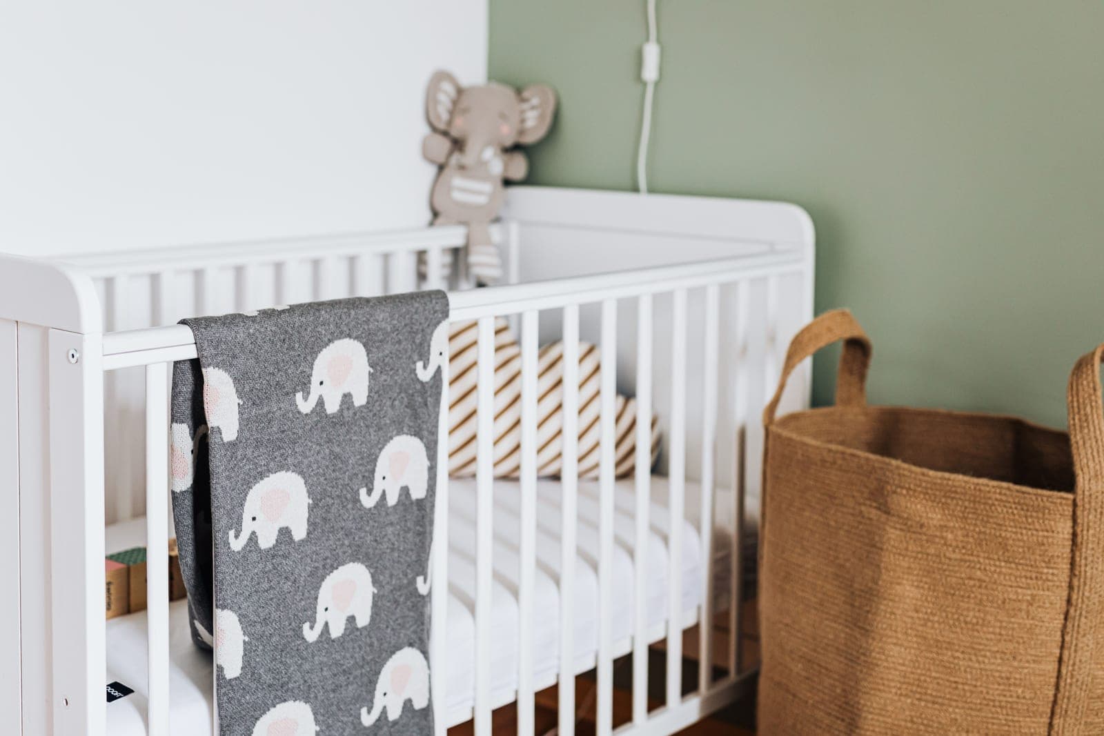A nursery with a white wooden crib and a hanging blanket