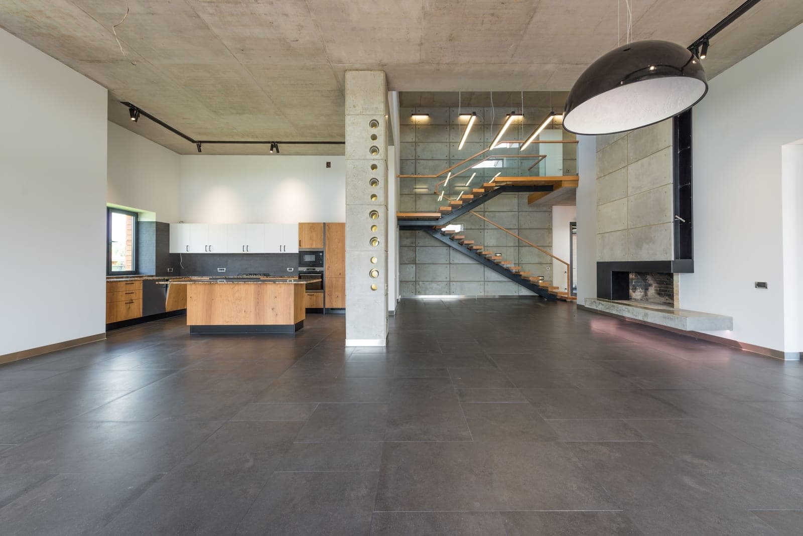 A spacious open-plan loft interior with a hallway and kitchen beyond