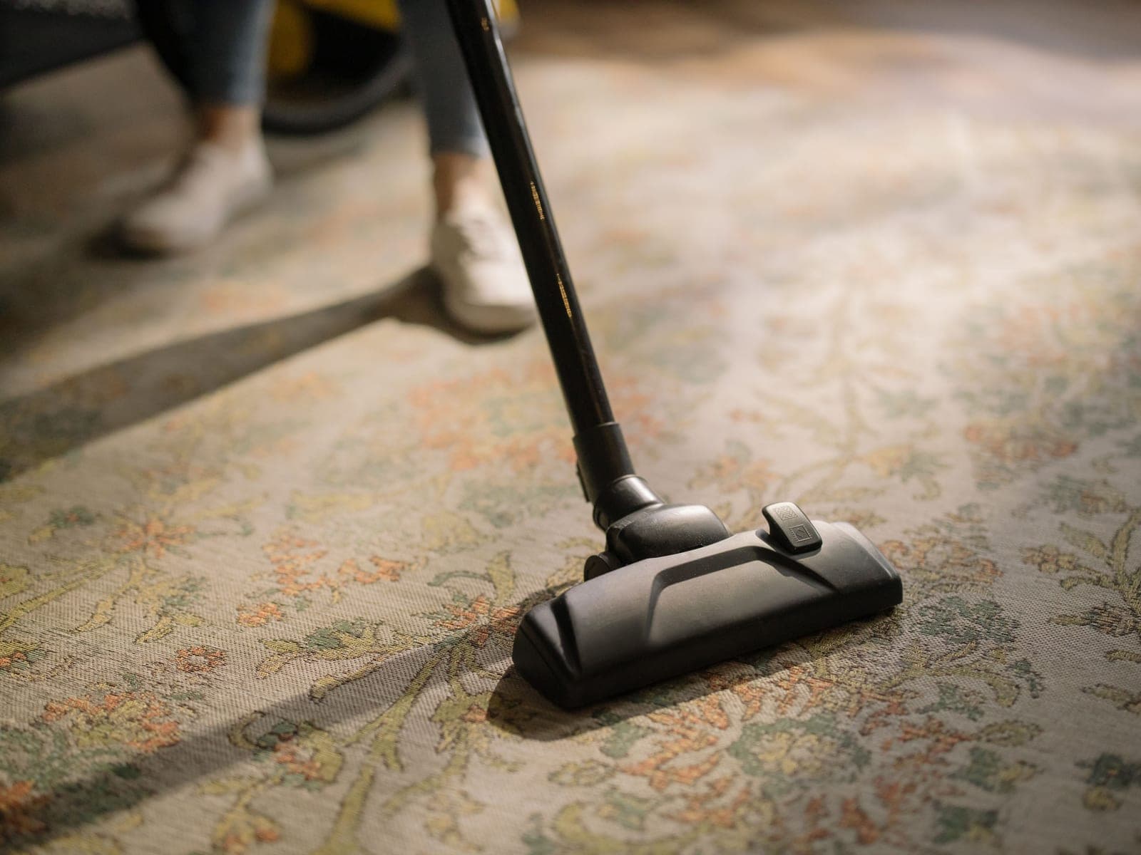 A vacuum cleaner head being pushed across a patterned carpet